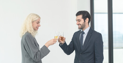 businessman and businesswoman toasting with champagne glasses in modern office.