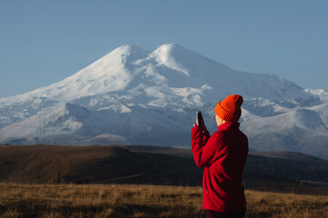 Fototapeta na wymiar a girl takes pictures of Elbrus on her phone
