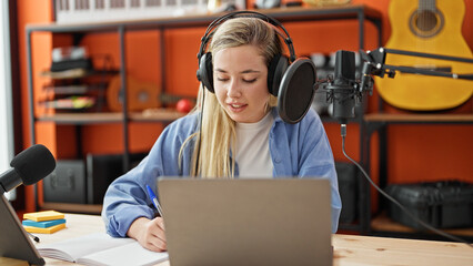 Young blonde woman reporter in a radio show at music studio