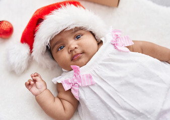 African american baby lying on floor wearing christmas hat at home