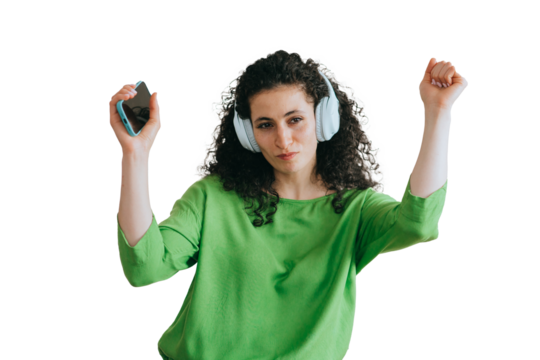 Full of energy young curly woman listening music using headphones and mobile phone against transparent background. Leisure, celebration, holiday concept, mockup.