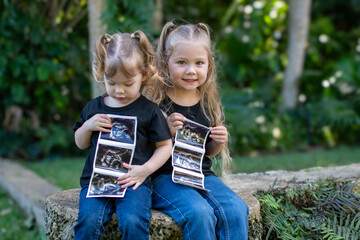 Pregnancy announcement by siblings. Social media pregnancy announcement. Big sister. The third child in a family. Two kids holding a sonogram of a new baby 