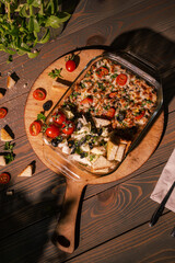 Beef Lasagna with mozzarella cheese, tomatoes and basil on a wooden board