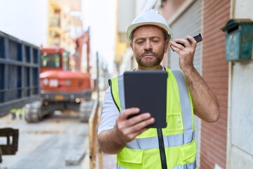 Middle age man architect listening voice message by smartphone using touchpad at street