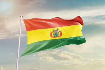 Bolivia national flag waving in beautiful sky. The symbol of the state on wavy silk fabric.
