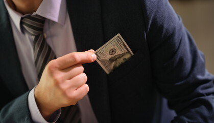 Businessman taking 100 dollar bill out of jacket pocket closeup. Bribery concept