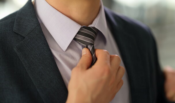 Elegant businessman in suit straightening tie on shirt closeup. Stylish male image business style concept
