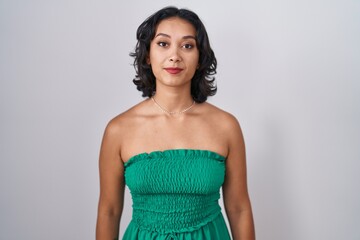 Fototapeta premium Young hispanic woman standing over isolated background relaxed with serious expression on face. simple and natural looking at the camera.