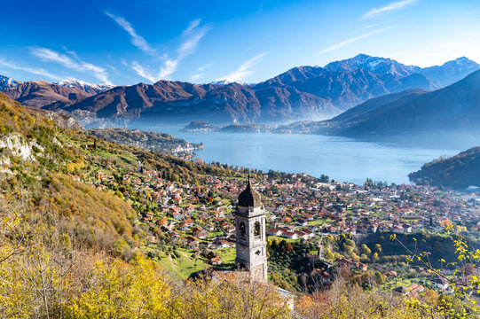 Lake Como photographed from Ossuccio, showing mountains, Bellagio, the town of Ossuccio, and the Church of the Madonna del Socco, in autumn.
