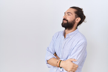 Hispanic man with beard wearing casual shirt looking to the side with arms crossed convinced and confident