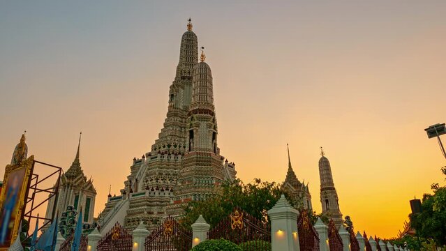 .Time lapse Phra Prang Wat Arun outstandingly beautiful along the Chao Phraya River.scenery sunset behind the large illuminated temple Wat Arun the biggest and tallest pagoda in the world..