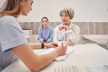 Taking care of health. Positive minded elderly woman smiling while looking at doctor