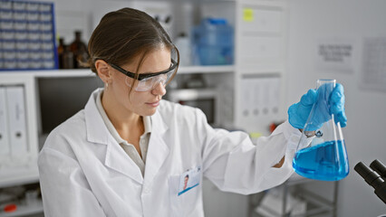Attractive young hispanic female scientist measuring liquid in a test tube, engrossed in her...