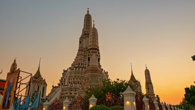 .Time lapse scenery sunset behind the large illuminated temple Wat Arun the biggest and tallest pagoda in the world beside Chaophraya river Bangkok Thailand..larger pagoda popular landmark in Bangkok