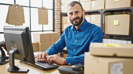 Young hispanic man ecommerce business worker using computer smiling at office