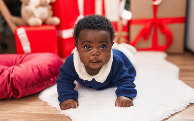 African american baby lying on floor by christmas gifts at home