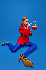 Young lady dressed unusual, freaky, bright outfit, wearing blue tights, red jacket and animal...