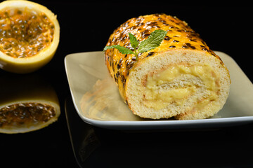 a passion fruit roulade on a reflective black background,