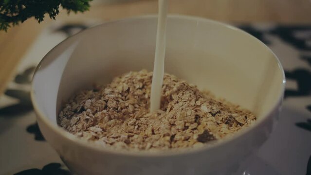 Woman pouring milk into a cereal breakfast bowl