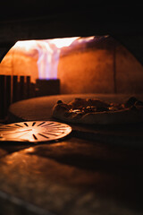 Tasty pizza being cooked in a rustic stone oven at an italian restaurant