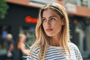 Young blonde woman looking to the side with serious expression at street