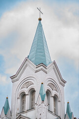 Gold christian cross shining in the top of a bright blue tower orthodox church in Latvia, Riga