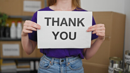 Young blonde woman volunteer holding thank you message at charity center