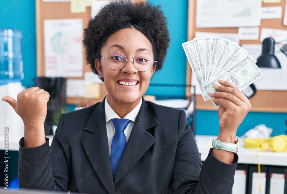 Sticker beautiful african woman with curly hair holding money at the office pointing thumb up to the side sm