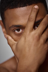 Fototapeta premium close up of handsome appealing african american man with hand in front of face, fashion concept