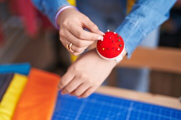 Young chinese woman tailor holding pin at clothing factory