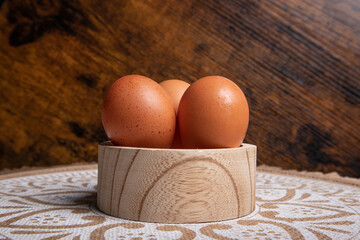 eggs, three eggs placed on a circular wooden container, at the base you can see a mat with mandalas...