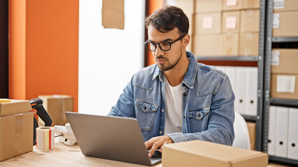 Young hispanic man ecommerce business worker using laptop at office