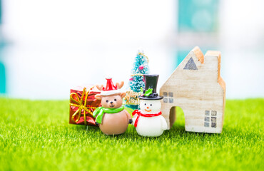 Miniature Snowman and Reindeer doll with miniature house and gift box with space on blurred background, outdoor day light, Happy Christmas background idea