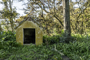 Fototapeta na wymiar A cement doghouse outside surrounded by trees and abundant grass