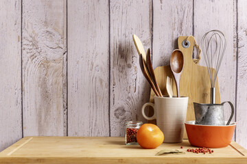 wooden and fiber kitchen utensils on a bamboo board along with red peppercorns, a tomato and bay...