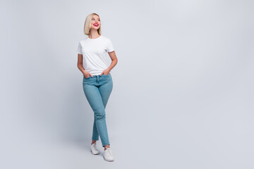 Full length photo of adorable satisfied girl wearing trendy clothes hands in pockets looking empty space isolated on grey color background