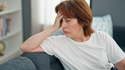 Middle age woman stressed sitting on sofa home