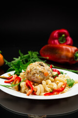 cooked pasta with meatballs, peppers and herbs with spices in a plate