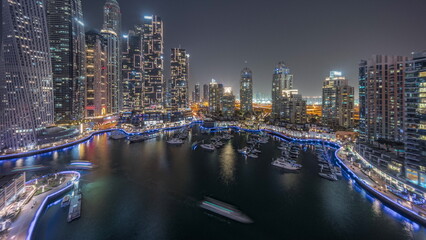 Fototapeta premium Dubai marina tallest skyscrapers and yachts in harbor aerial day to night timelapse.