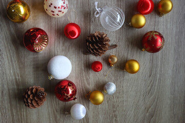 Pine cones and red, golden and white Christmas ornaments on wooden background. Top view.