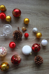 Pine cones and red, golden and white Christmas ornaments on wooden background. Top view.