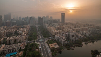 Naklejka premium Skyscrapers in Barsha Heights district and low rise buildings in Greens district aerial night to day timelapse.