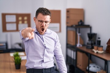 Young hispanic man at the office pointing displeased and frustrated to the camera, angry and...
