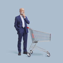 Pensive businessman standing behind a shopping cart
