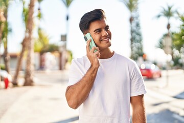 Young hispanic man smiling confident talking on the smartphone at street