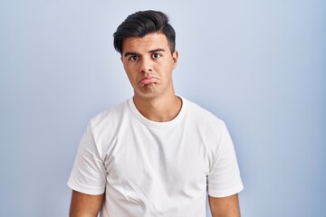 Hispanic man standing over blue background depressed and worry for distress, crying angry and afraid. sad expression.
