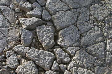 Detailed view of way with deep grooves. View of dirt road fragment. Dry land with stones. Abstract natural textured background. Stones and pebbles on the ground