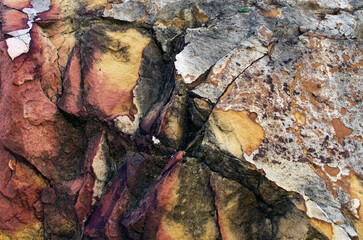 The multi-colored exposed sandstone rock and mineral layers. Sandstone pattern, geological texture. Bright red-brown stone background. Abstract background
