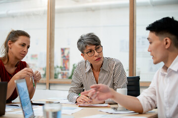 Businesswoman listening to coworkers during project meeting