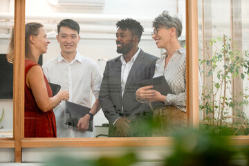 Fototapeta premium Coworkers discussing project while standing in meeting room